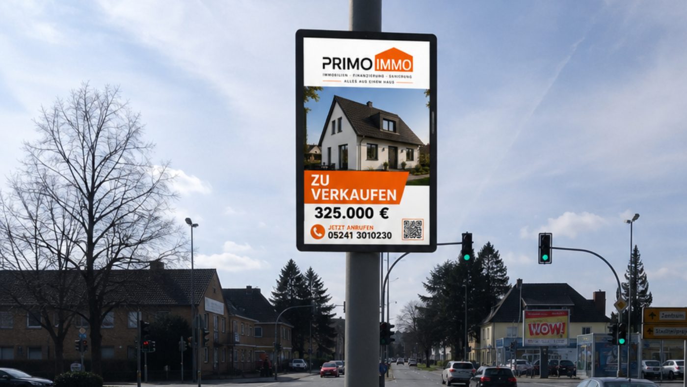 Werberahmen mit PrimoImmo-Objektplakat an einer Ampelkreuzung in Gütersloh